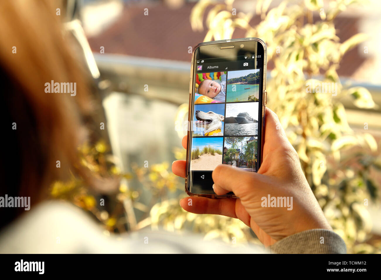 Mädchen mit Photo Gallery im Bildschirm Ihres Smartphones. Junge Frau, mit einem Handy in der Hand. Tausendjährige, Technologie. Stockfoto