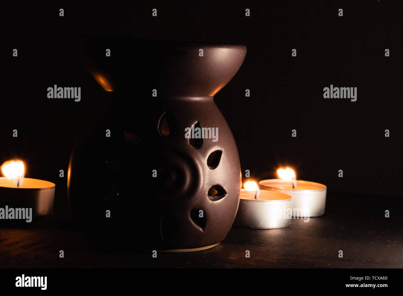 Traditionelle Aroma-diffusor mit Kerzen in der Rückseite, dunkles Bild mit hohem Kontrast Stockfoto