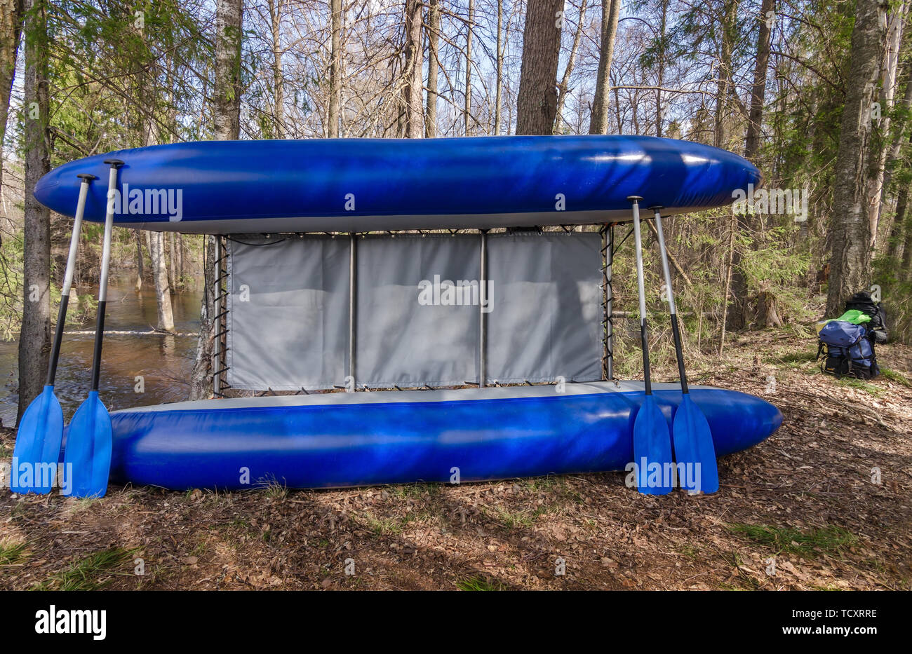 Blau Katamaran mit vier Ruder in der Nähe von Bäumen im Wald Stockfoto