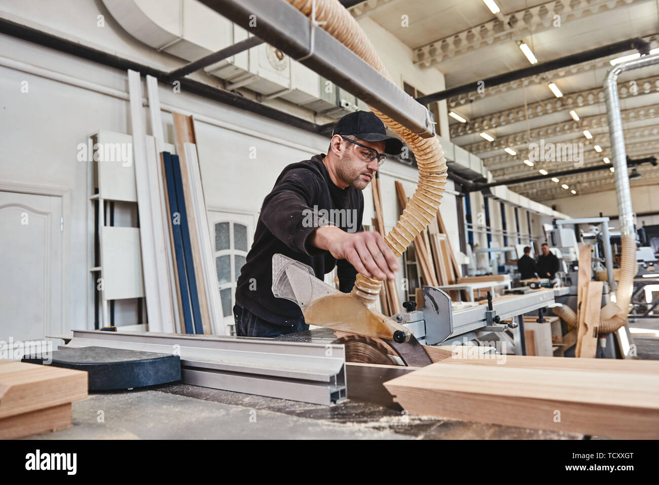 Sägen von Holz- auf eine Formatkreissäge. Holzbearbeitung und Schreinerei Produktion. Herstellung von Möbeln. Horizontale erschossen. Seitenansicht Stockfoto
