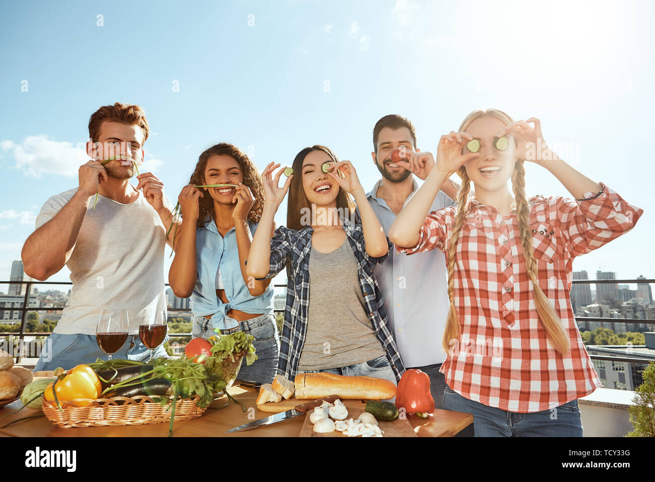 Zeit mit Freunden. Gruppe von Jungen und Fröhlichen Freunden in Freizeitkleidung Vorbereiten der Nahrung für die Grillparty und Spaß beim Stehen auf t Stockfoto