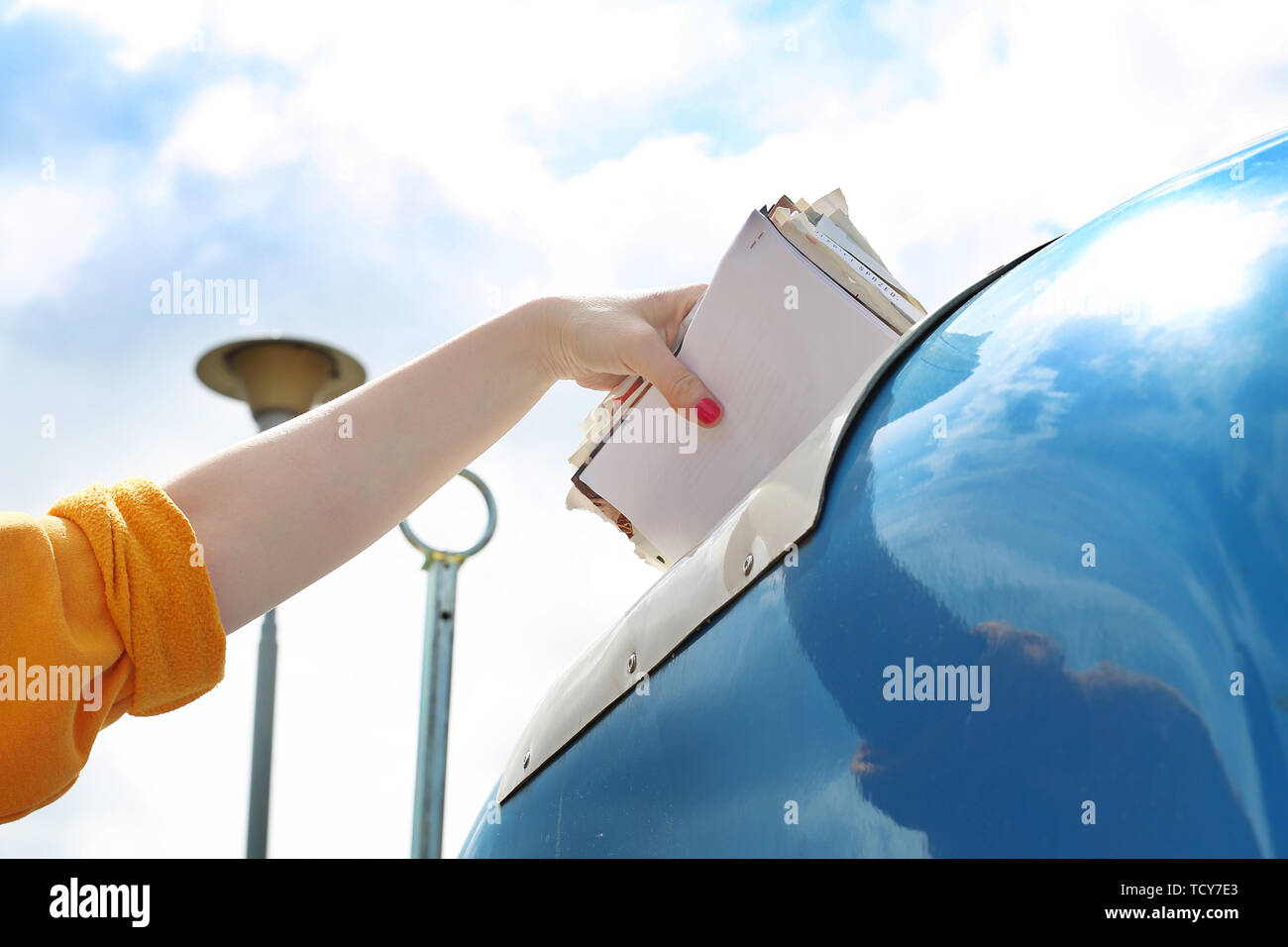 Recycling, eine Frau wirft Papier Abfall in einen blauen Container Stockfoto