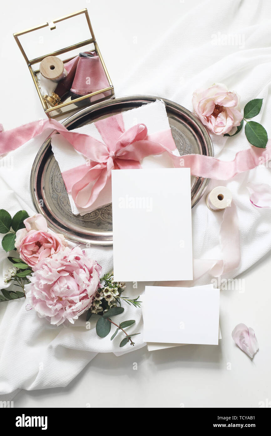 Feminine vertikale Hochzeit, Geburtstag Mock-up-Szene. Leeres Papier Grußkarten, Eukalyptus, Rosen, Pfingstrosen Blumen auf weißem Hintergrund. Golden Stockfoto