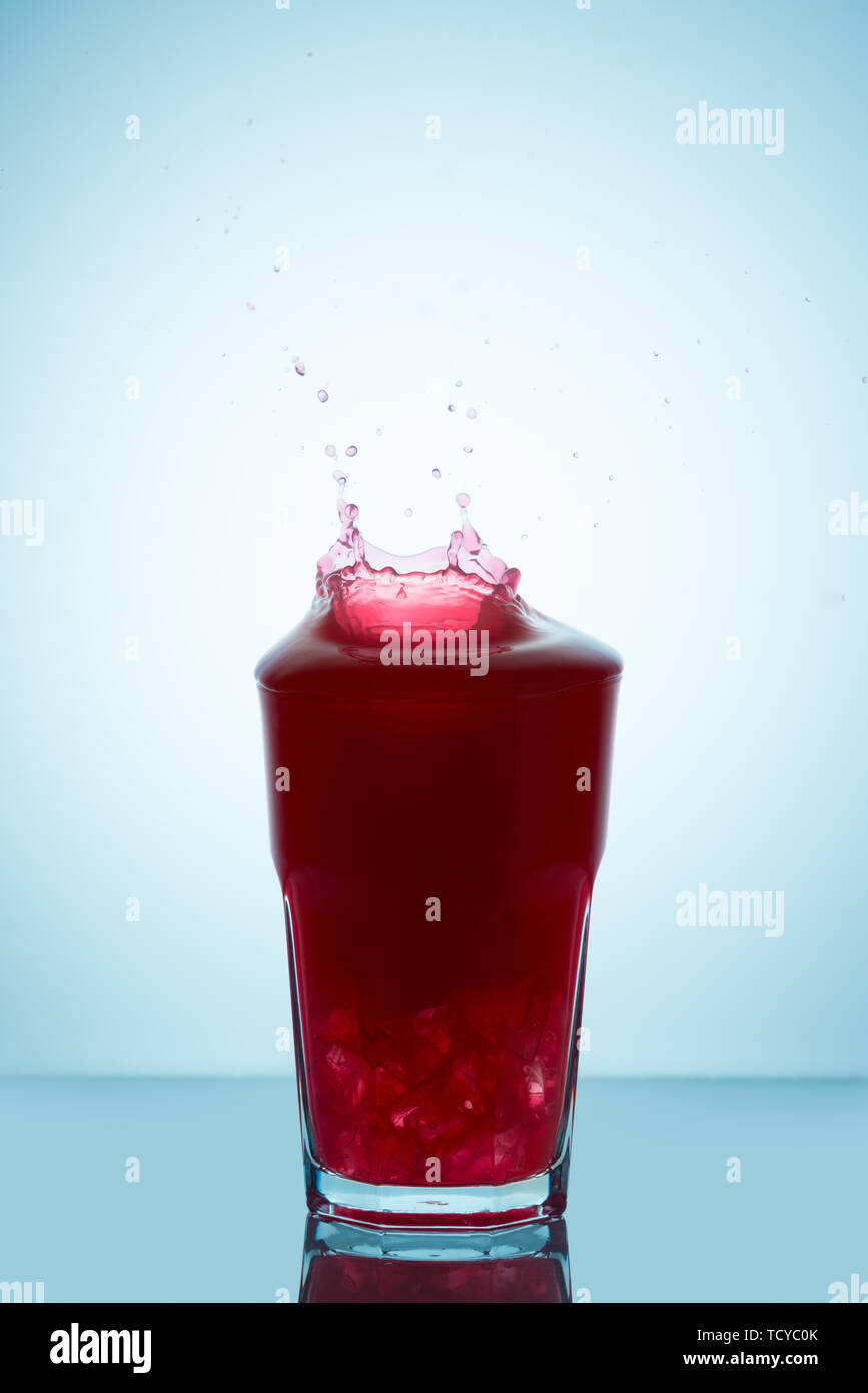 Spritzer auf ein Glas Himbeersaft stellvertretend für das Konzept der ohne einen Tropfen zu verschütten Stockfoto