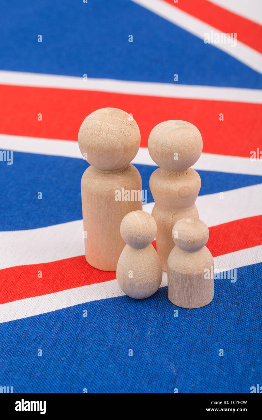 Kleine abstrakte Holzfiguren auf der Flagge von Union Jack. Für die demografische Entwicklung des britischen Familienlebens / britische Familieneinheit, Kernfamilie, Familienhaushalte. Stockfoto
