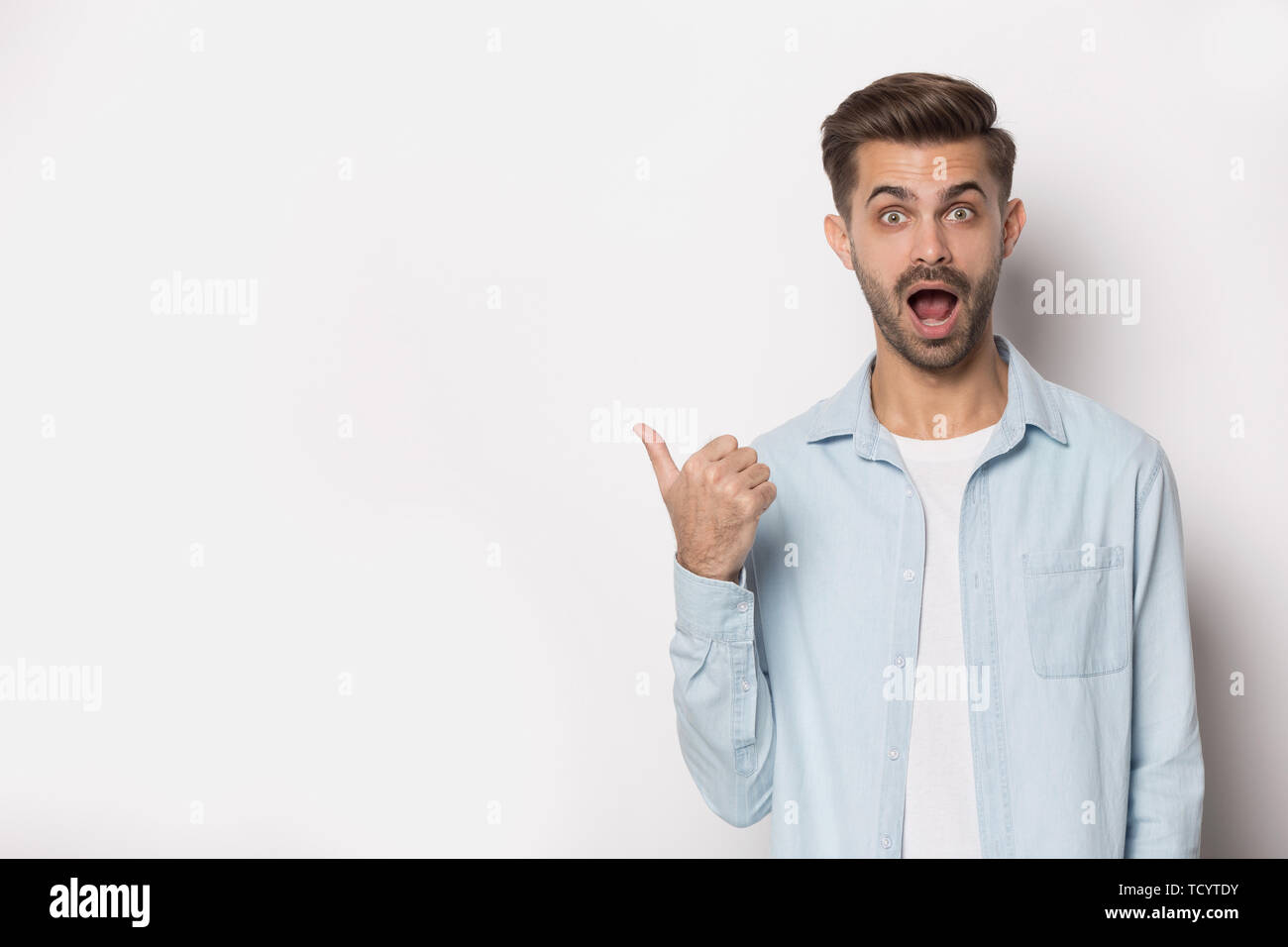 Guy geöffnetem Mund gawp bei camera Pointing Finger auf Copyspace Stockfoto