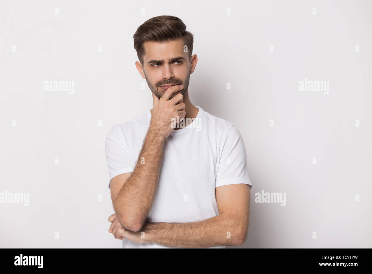 Nachdenklicher Kerl auf weißem Hintergrund touch Kinn isoliert Denken Stockfoto