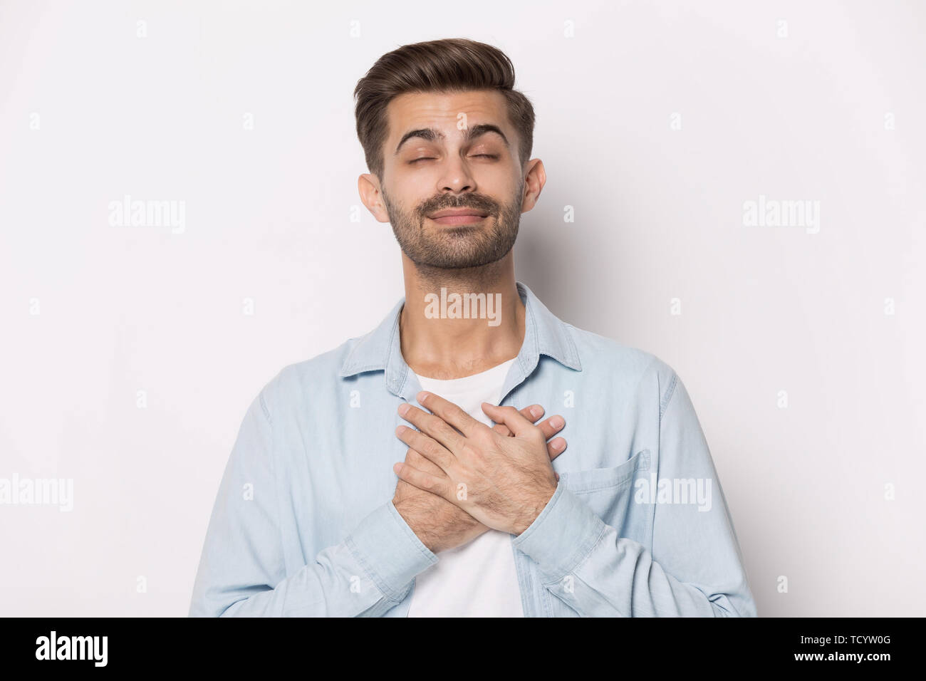 Guy geschlossenen Augen, Hände auf die Brust mit freundlichen Grüßen anfordern Stockfoto