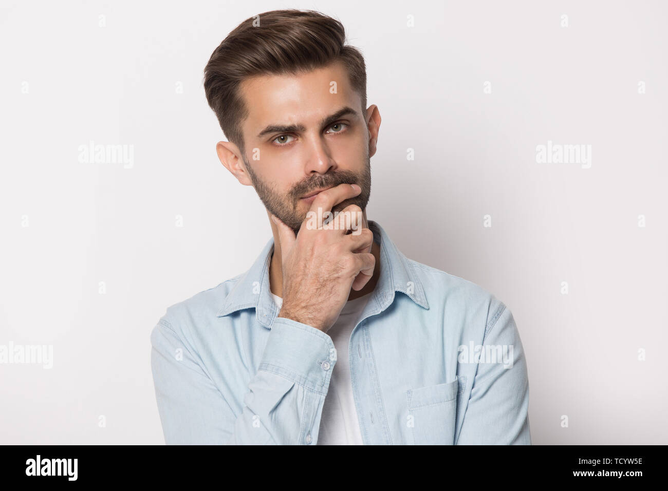 Nachdenklichen jungen Mann die Hand am Kinn Gefühl zweifelhaft Stockfoto