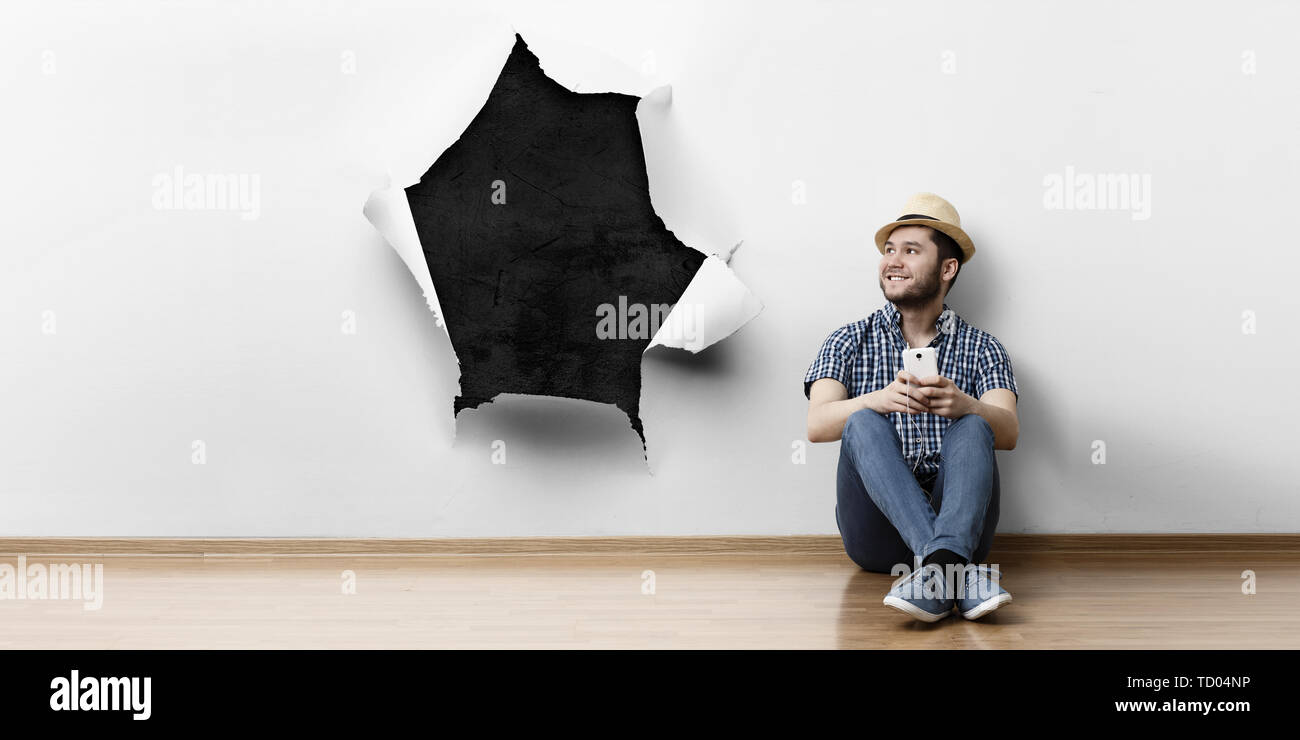 Junger Mann sitzen auf dem Boden, ein Moment für Konzept entspannen. Mixed Media Stockfoto