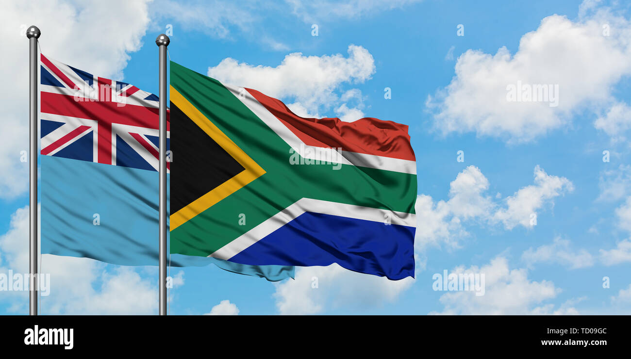 Fidschi und Südafrika Flagge im Wind gegen Weiße bewölkt blauer Himmel zusammen. Diplomatie Konzept, internationale Beziehungen. Stockfoto