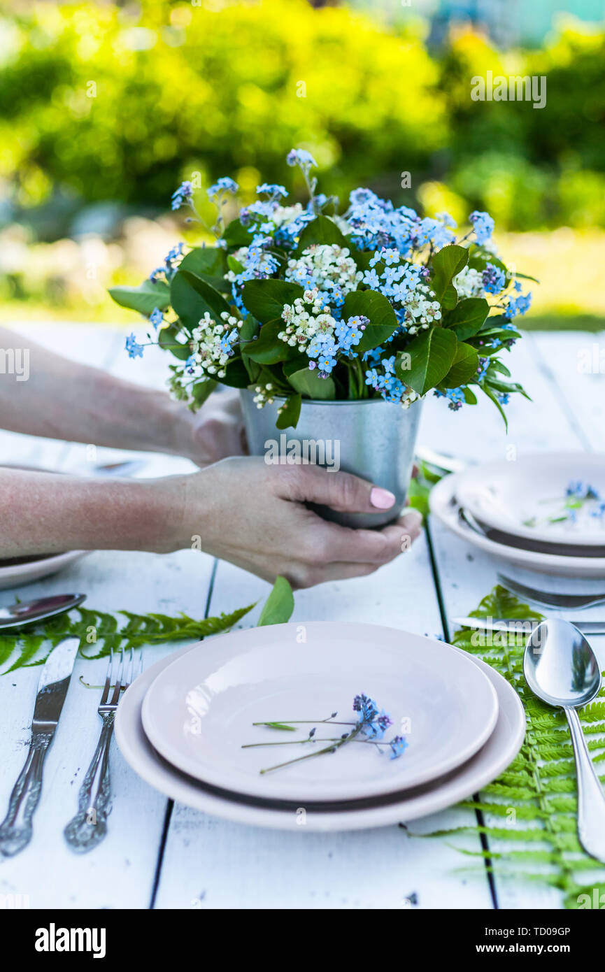 Florist halten elegantes Bouquet von blauen Vergißmeinnicht Blumen auf weißem Holztisch. Rustikale Dekoration Stockfoto