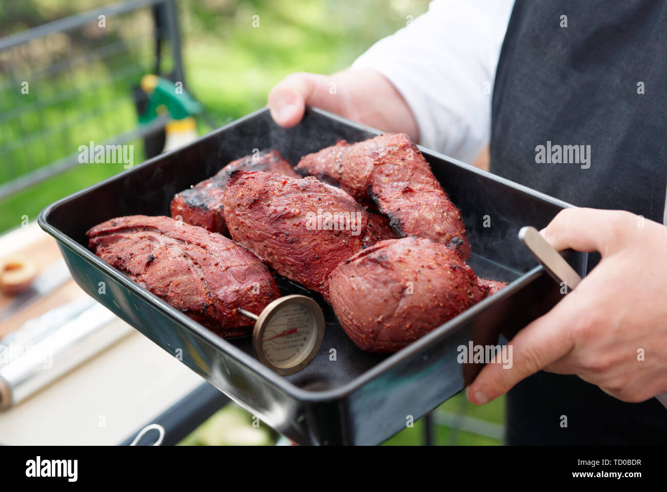 Koch Holding ein Fach mit gekochtem Fleisch, outdooe Schuß Stockfoto