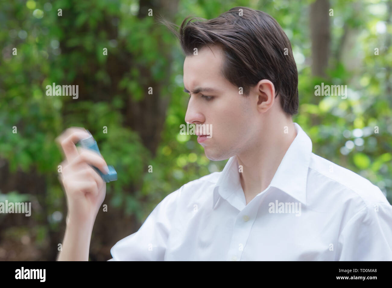 Junge Mann ist mit einem Asthma Inhalator und schütteln es vor Stockfoto