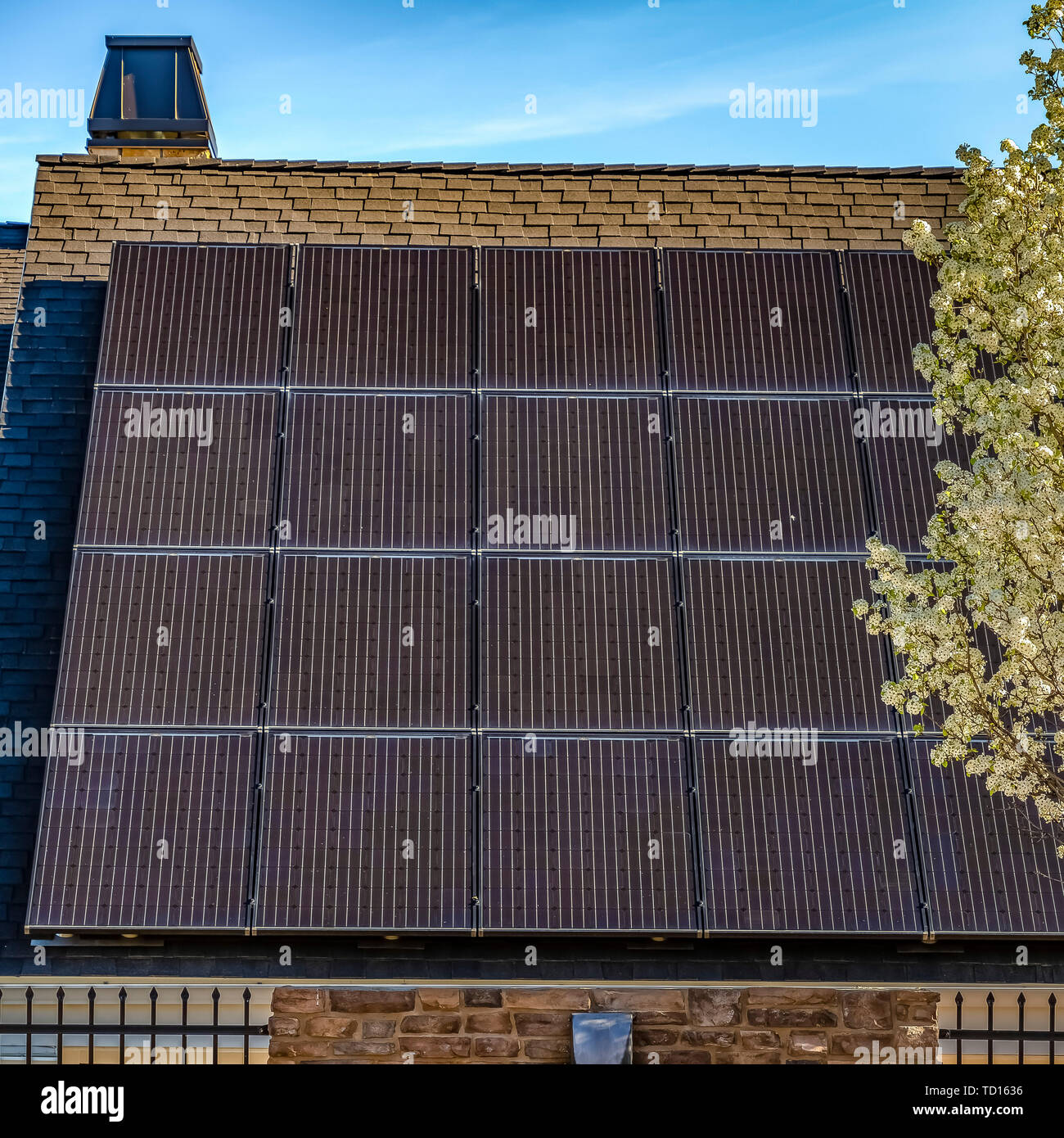 Quadratischen rahmen Solar Panel auf der dunklen Schrägdach eines Hauses gegen den blauen Himmel an einem sonnigen Tag Stockfoto