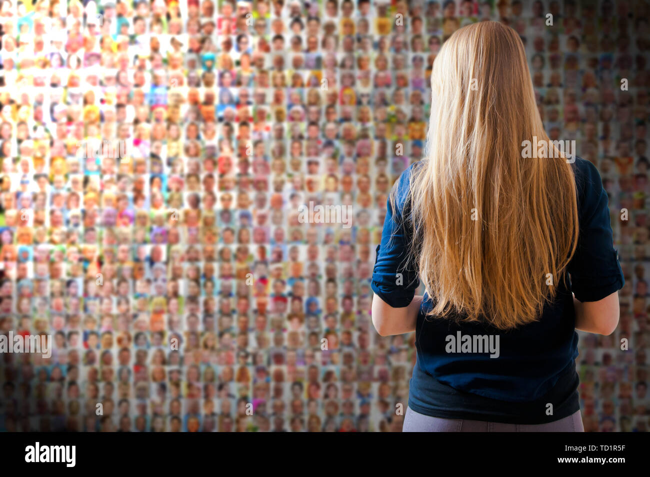 Blonde Frau vor einem Bildschirm oder einer Wand mit Tausenden von Menschen Gesichter - soziales Netzwerk und soziale Medien Konzept Stockfoto