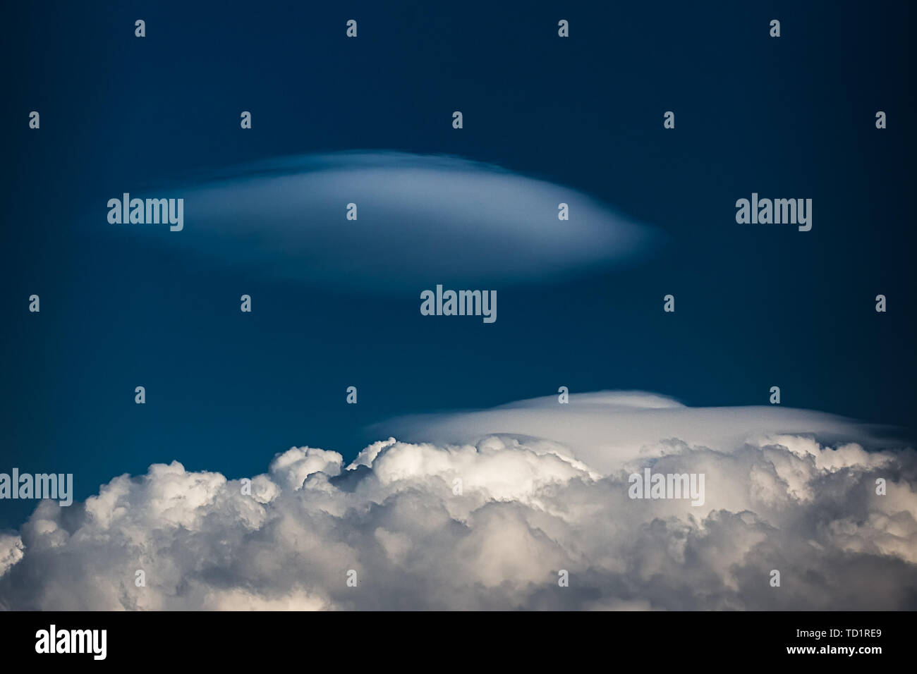 Seltene Linsenförmige Wolken Altocumulus lenticularis auf einem Cumulus Cloud vor einem blauen Himmel Stockfoto