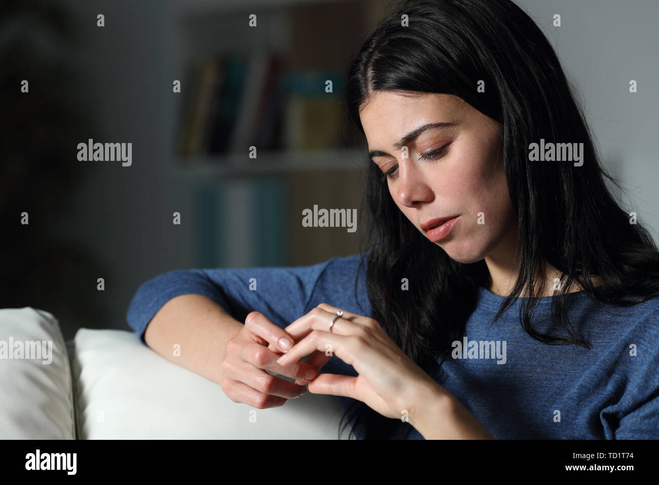 Verwirrt Frau an Engagement Ring sitzen auf einer Couch in der Nacht zu Hause suchen Stockfoto