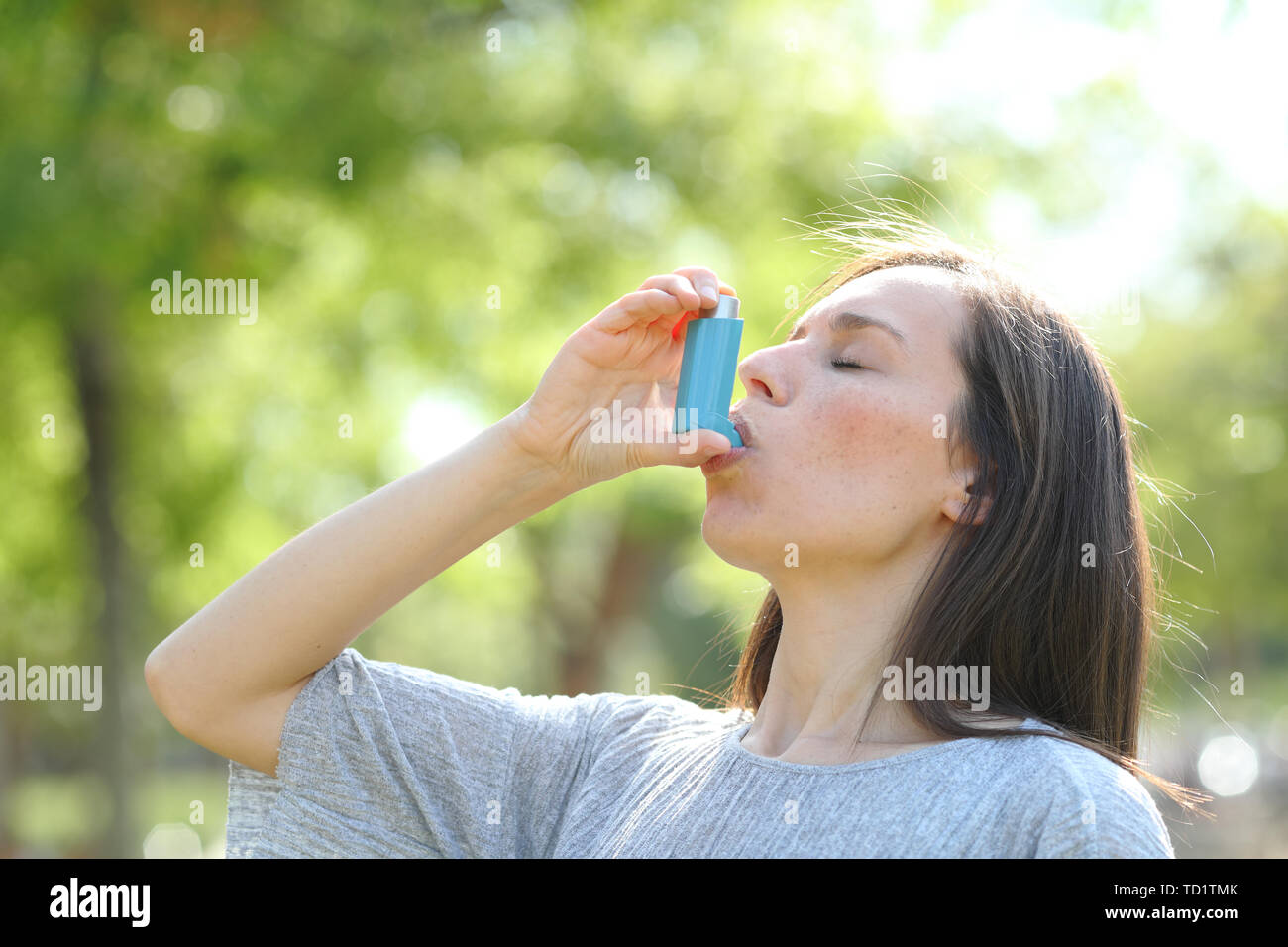 Die Frau ist mit einem Asthma Inhalator im Freien in einem grünen Park Stockfoto