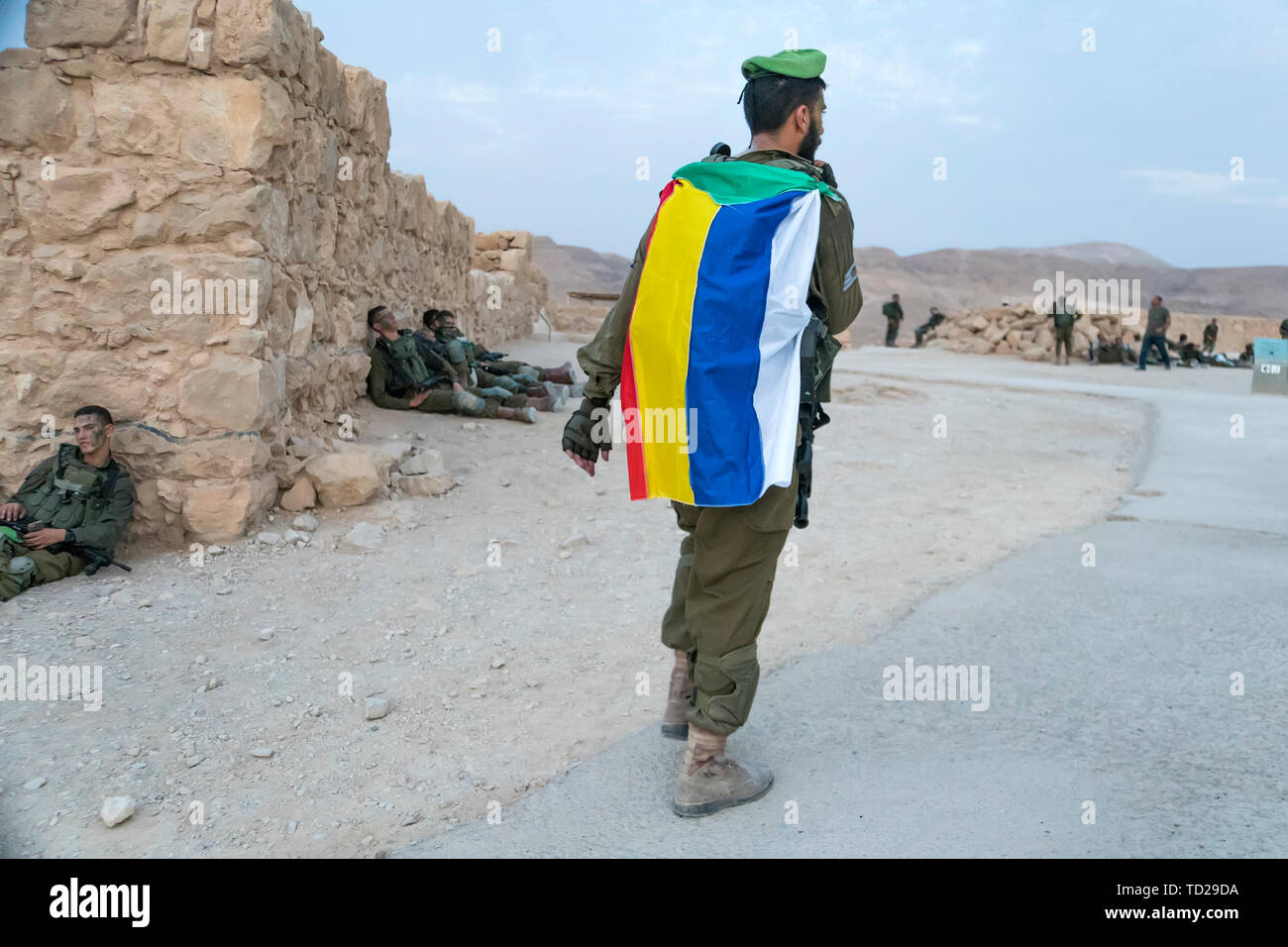 Masada, Israel. 23. Oktober 2018: Soldat mit einem absteigenden Grün, Rot, Gelb, Blau und Pfingstmontag streifen Flagge von Drusen während des Krieges spielen. Stockfoto