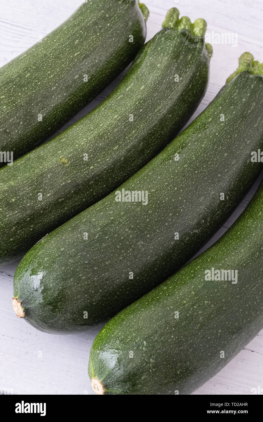 Schottische Zucchini stellten sich in einer Reihe auf einem weißen beplankten Holzbrett eine Ihrer "5 am Tag" für gesunde Ernährung. Stockfoto