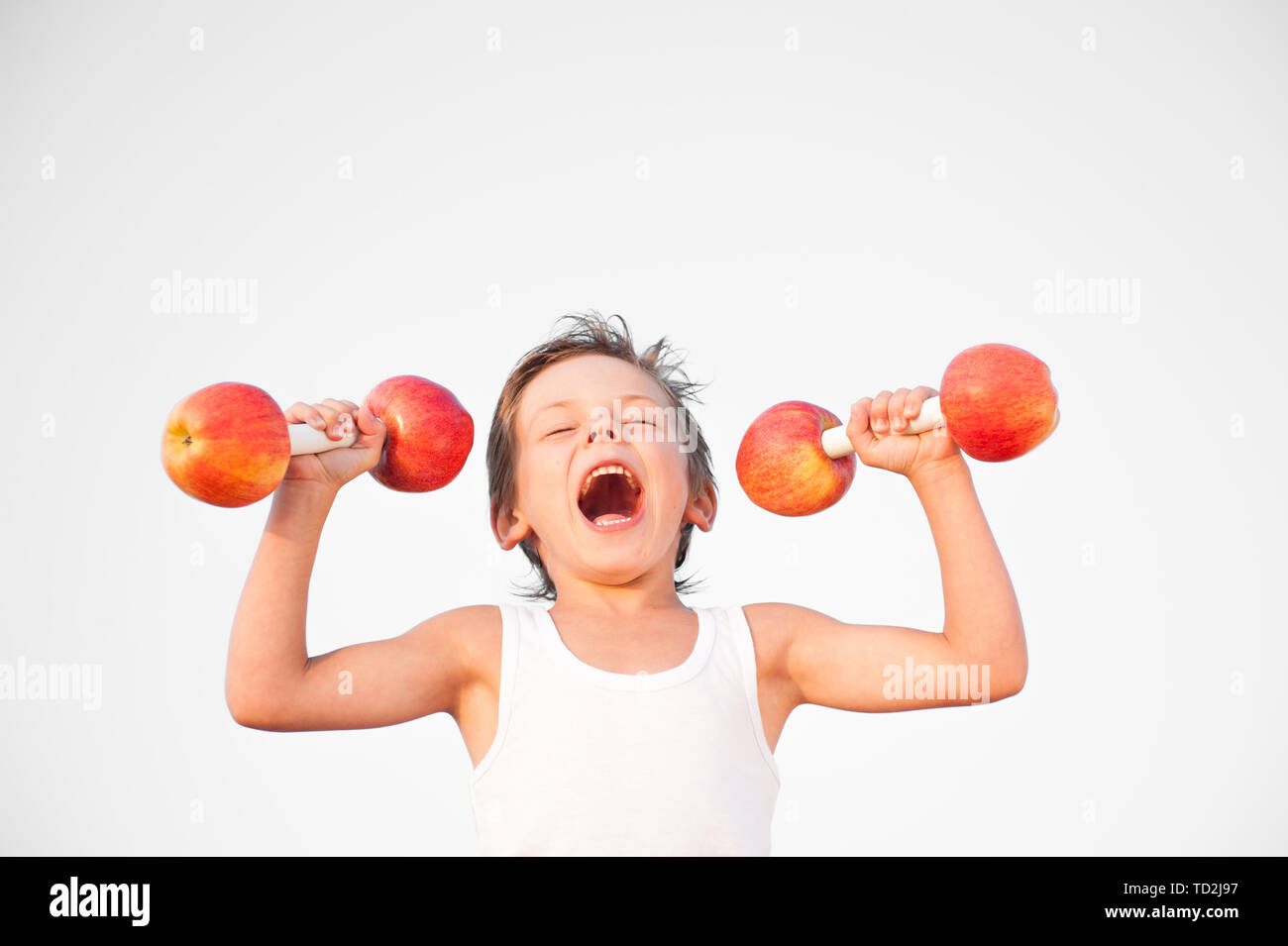 Lustige gesunde starker Junge Hanteln aus Äpfeln mit Mühe im Sommer Workout Stockfoto