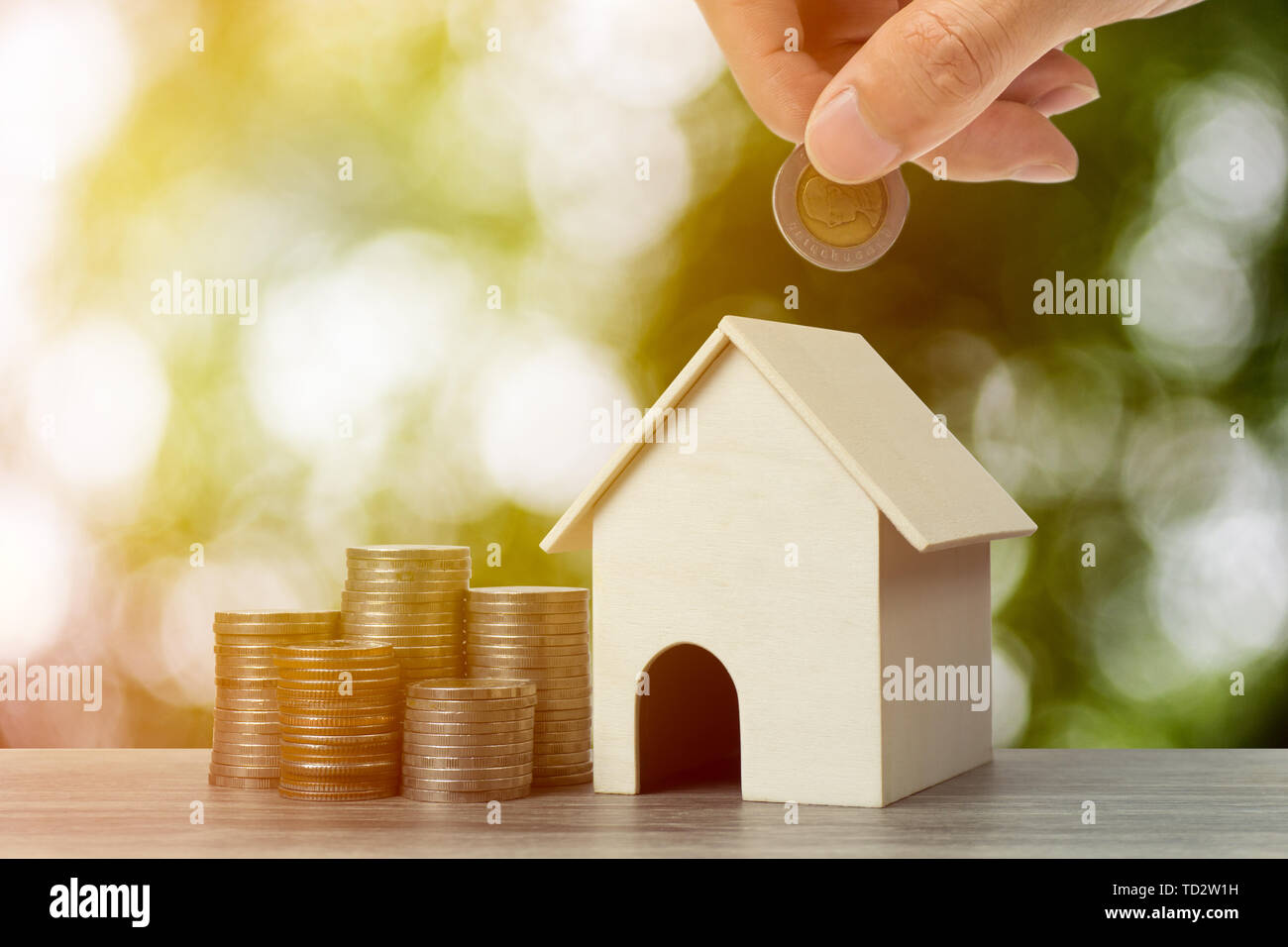 Geld sparen, Darlehen, Hypothek, eine Eigenschaft Investition für zukünftige Konzept. Ein Geschäftsmann Hand Geld Münze über kleine Residenz Haus und Stac Stockfoto