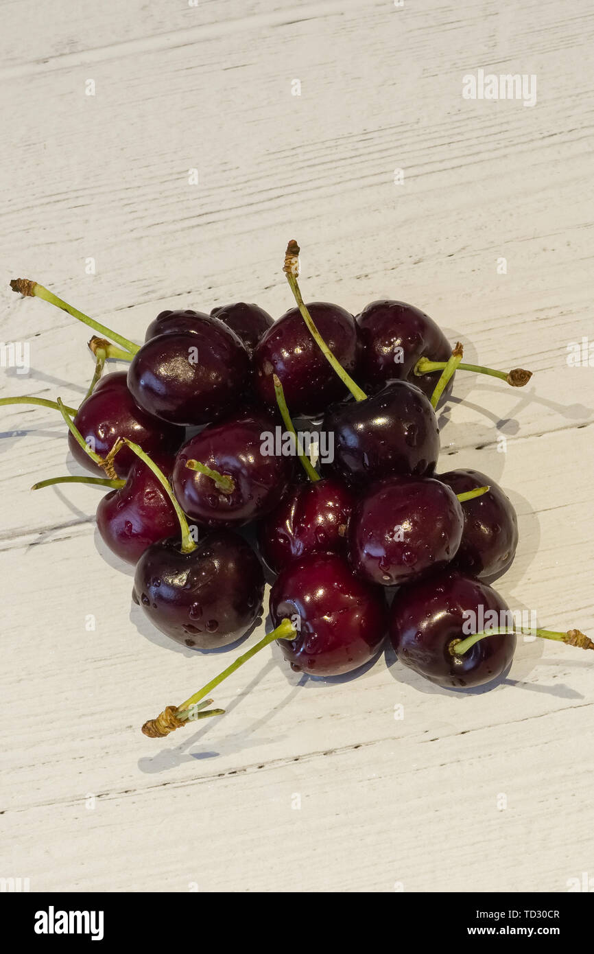 Ein Bündel neu abgeholt Kirschen auf einem weißen Beplankten lackiert Board Stockfoto