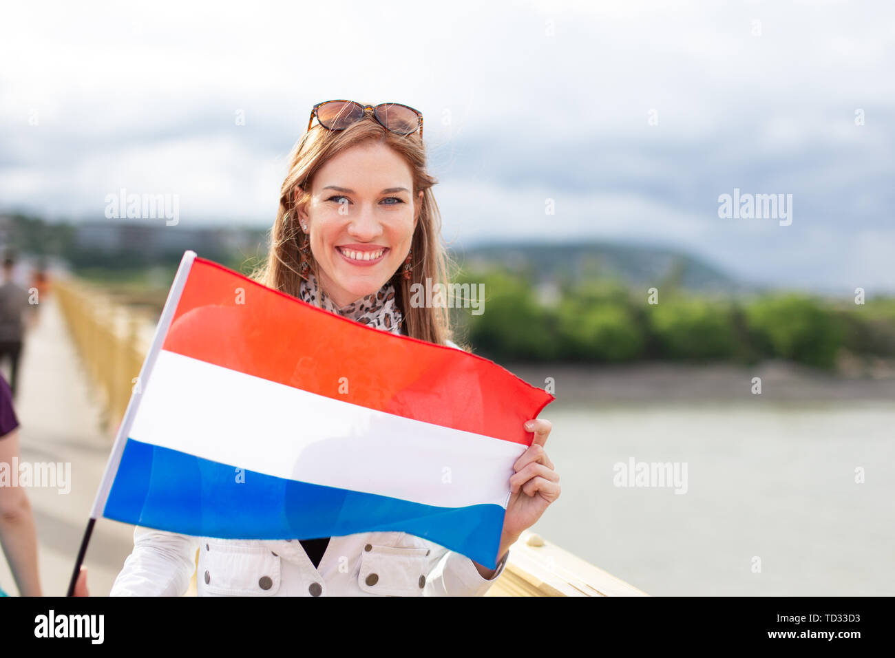 Glückliche junge Frau mit niederländischer Flagge mit toothy Lächeln, im Freien Stockfoto