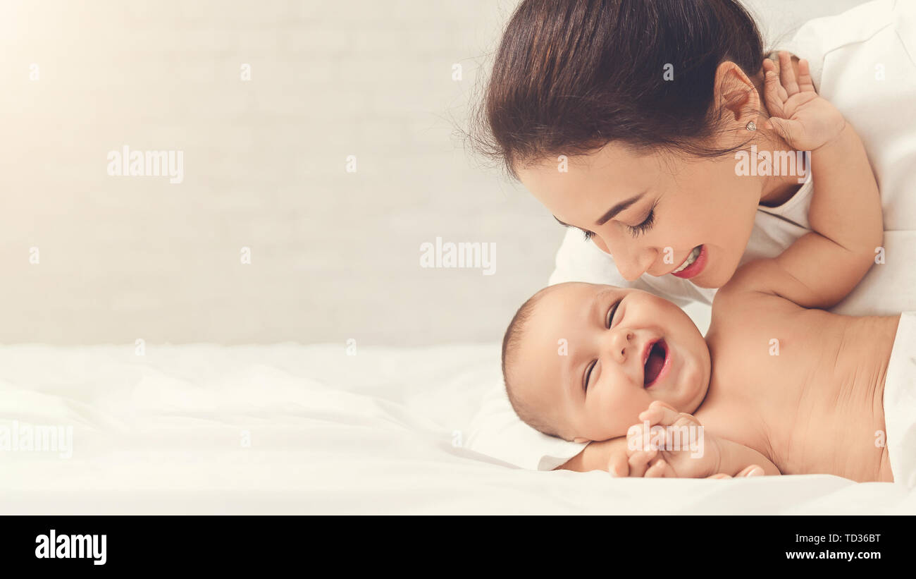 Mutter kitzeln Ihr Baby spielt im Bett zu Hause Stockfoto