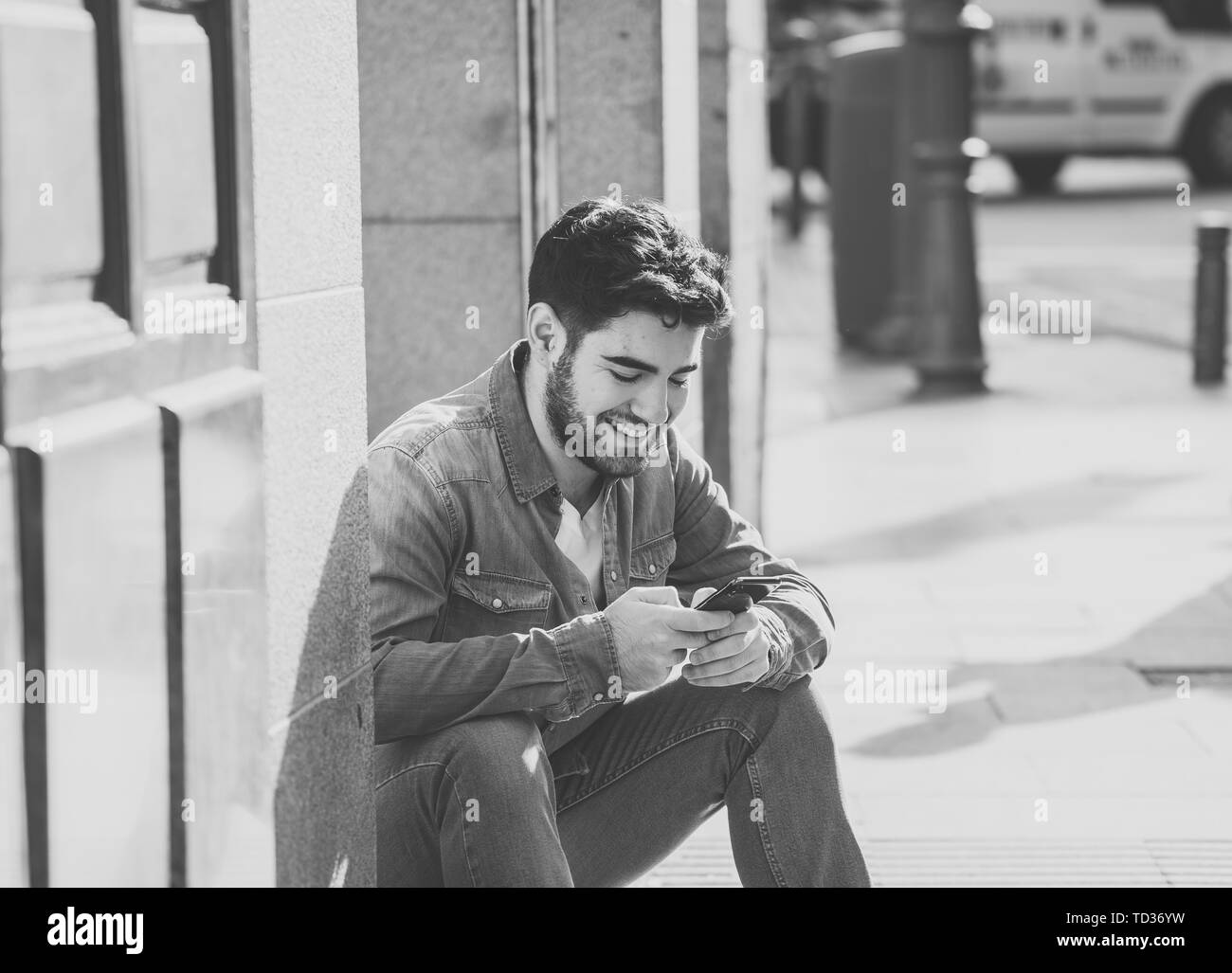 Fashion College Mann in den zwanziger Jahren glücklich Kontrolle blog oder im Internet chatten mit Freunden auf Smart Mobile Phone App in der Europäischen Freien Stadt. Stockfoto