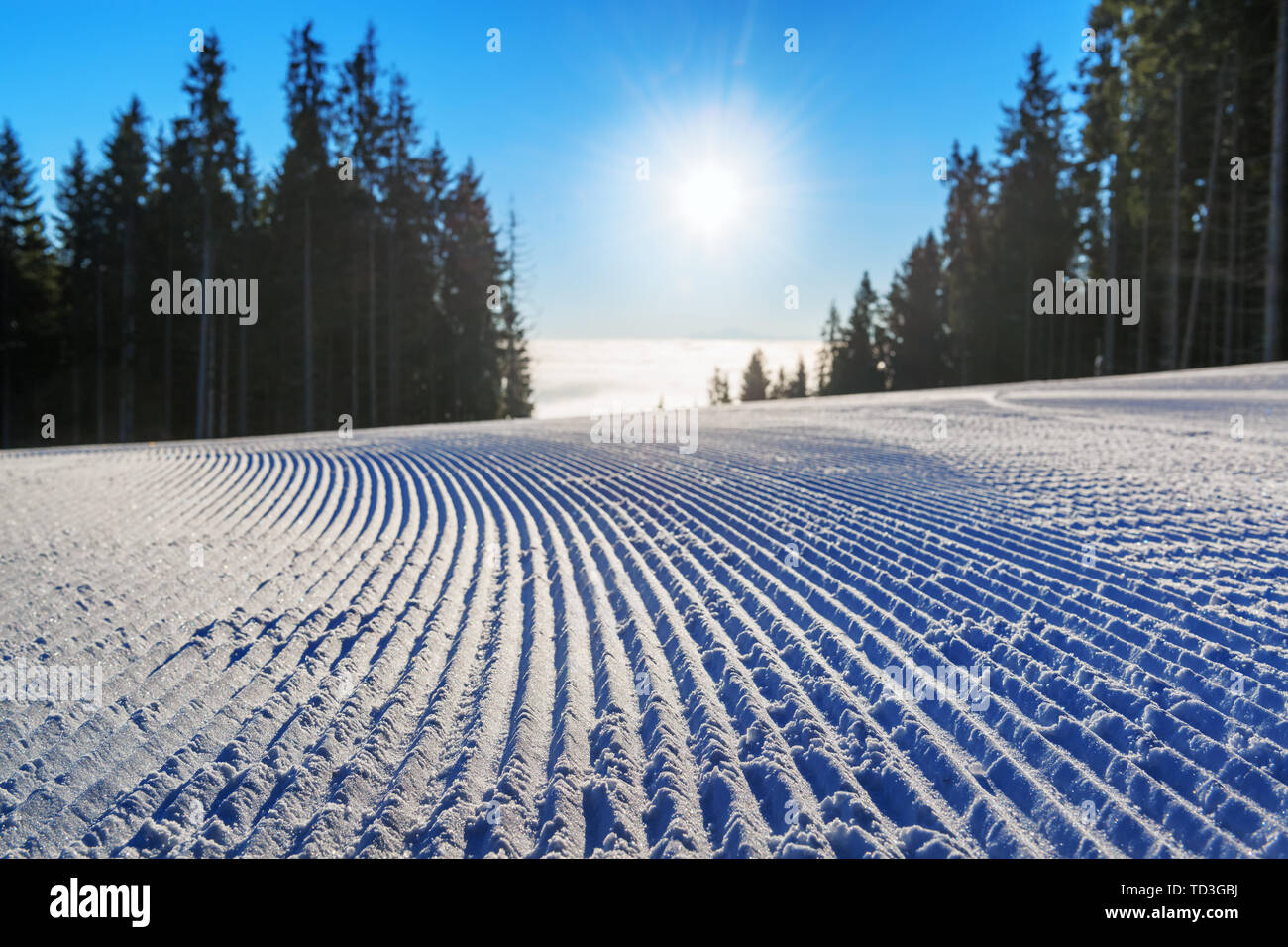 Frisch präparierte Skipiste close-up gegen die aufgehende Sonne in den Bergen Stockfoto