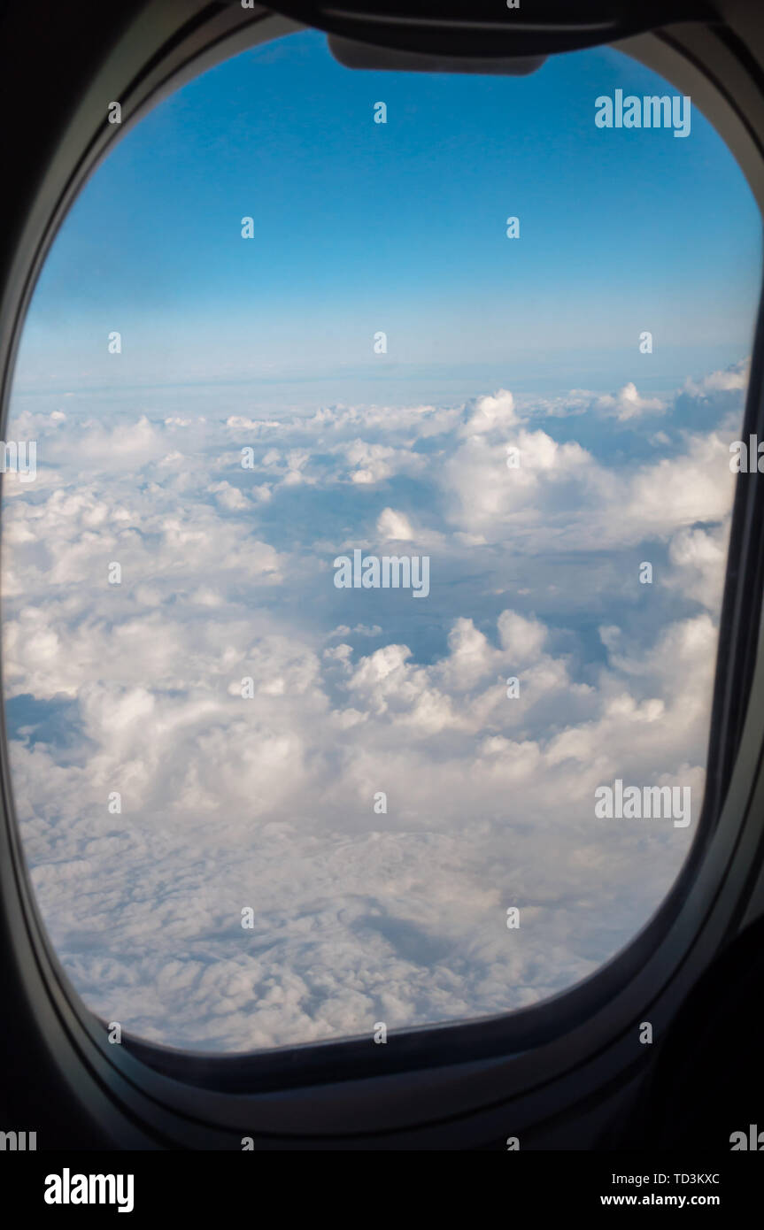 Höhe Reisen über den Wolken, durch das "Bullauge" eines Flugzeugs Stockfoto