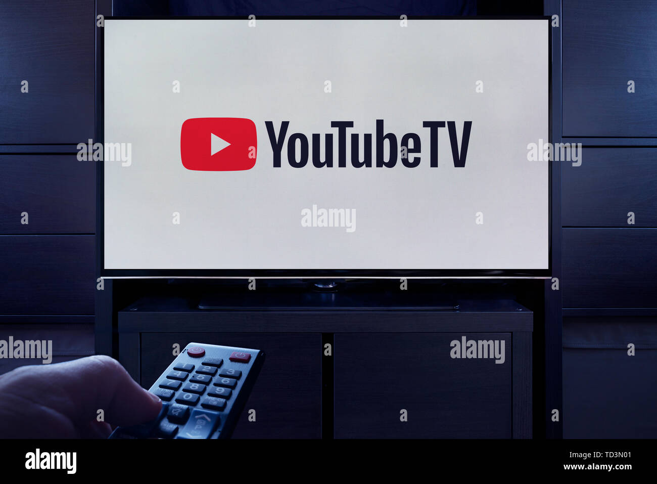 Ein Mann Punkte eine TV-Fernbedienung auf den Fernseher, die zeigt das Logo für die YouTube TV on Demand Video Streaming Service (nur redaktionelle Nutzung). Stockfoto