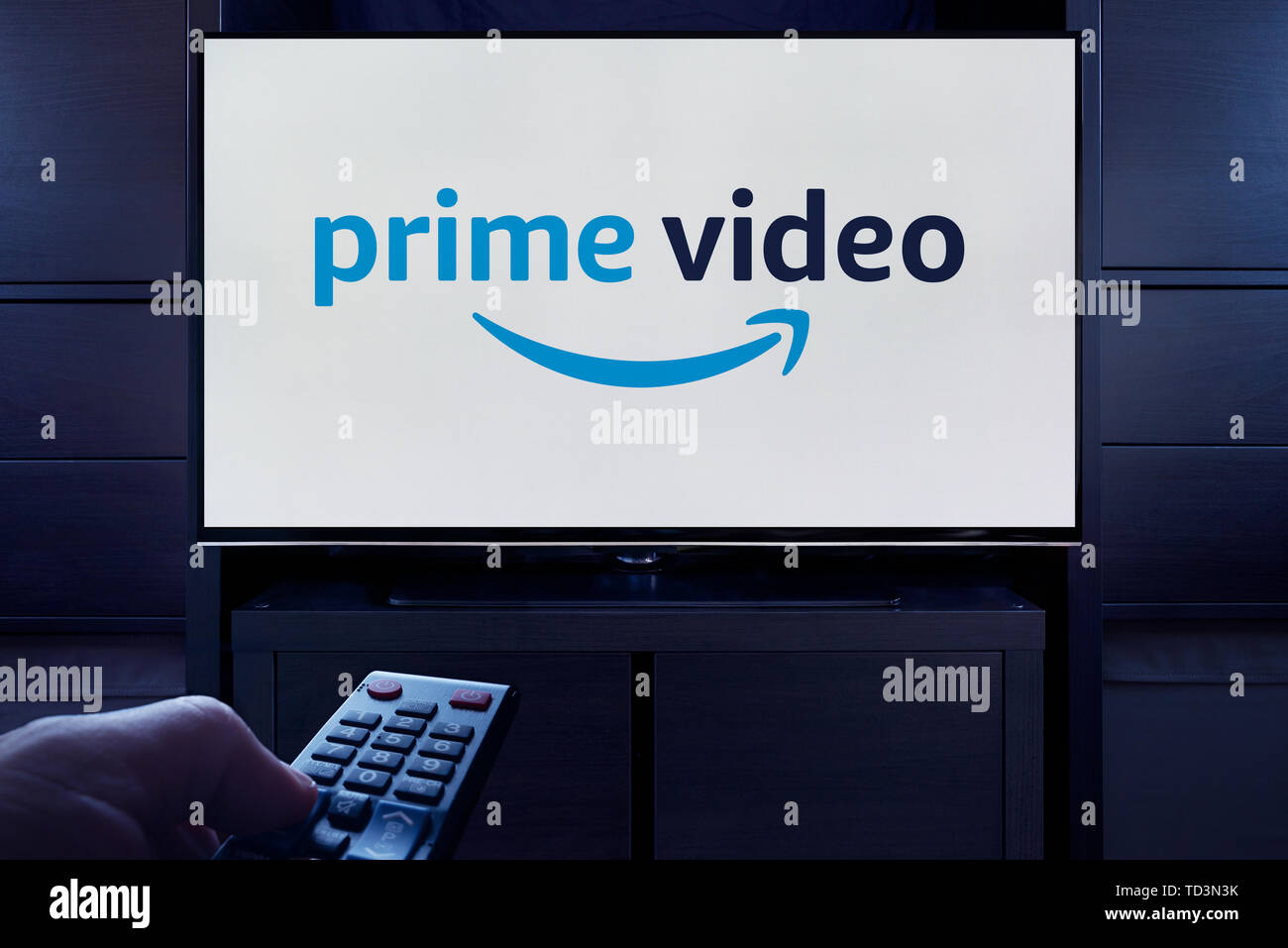 Ein Mann Punkte eine TV-Fernbedienung auf den Fernseher, die zeigt das Logo für die Prime Video on Demand Video Streaming Service (nur redaktionelle Nutzung). Stockfoto