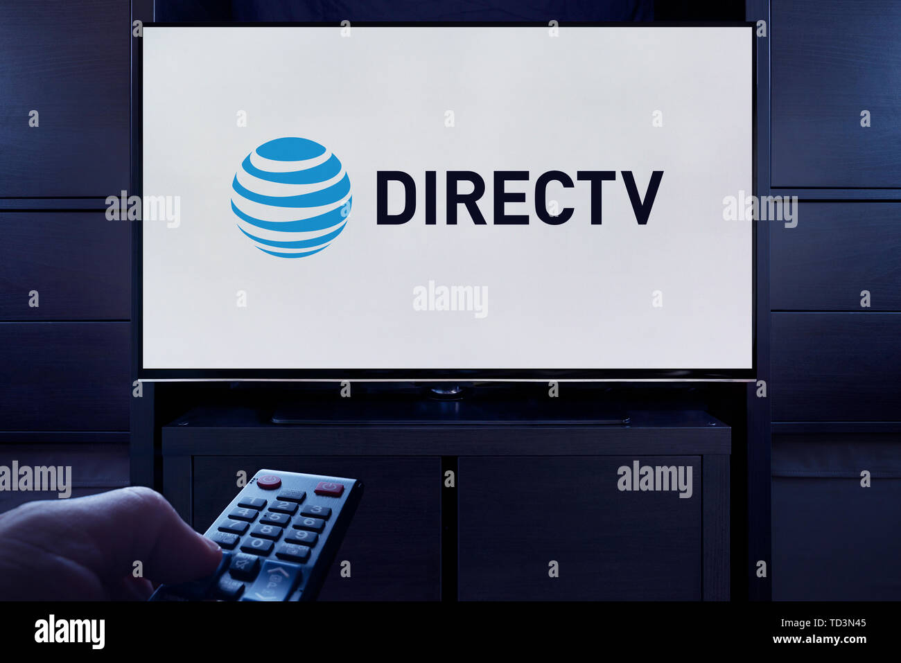 Ein Mann Punkte eine TV-Fernbedienung auf den Fernseher, die zeigt das Logo für den DirecTV on demand Video Streaming Service (nur redaktionelle Nutzung). Stockfoto