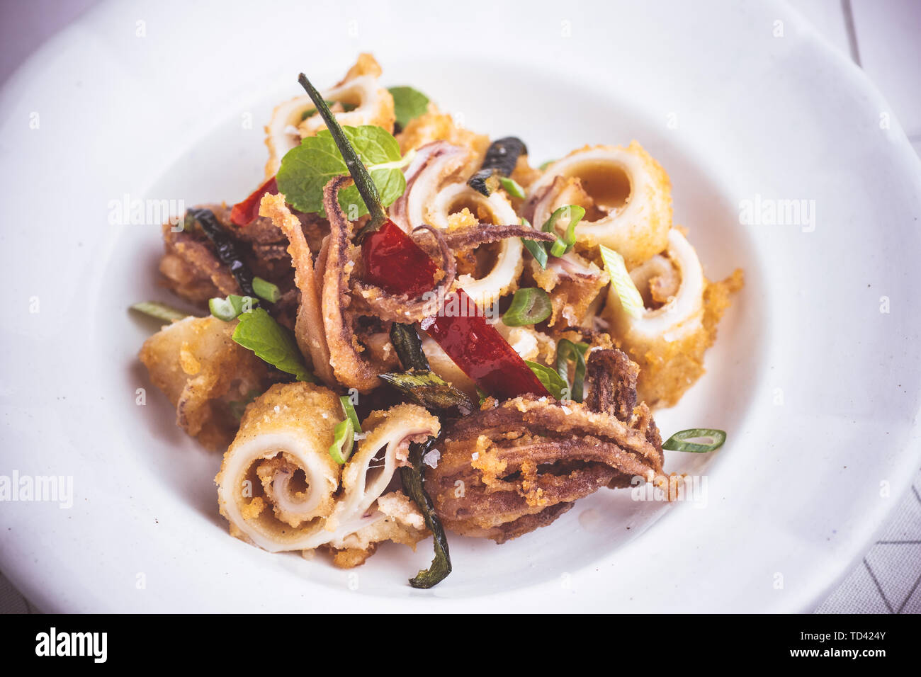 Frisch gebratenen Tintenfisch Tintenfisch mit Paprika Pfeffer in der rustikalen weiße Platte Stockfoto