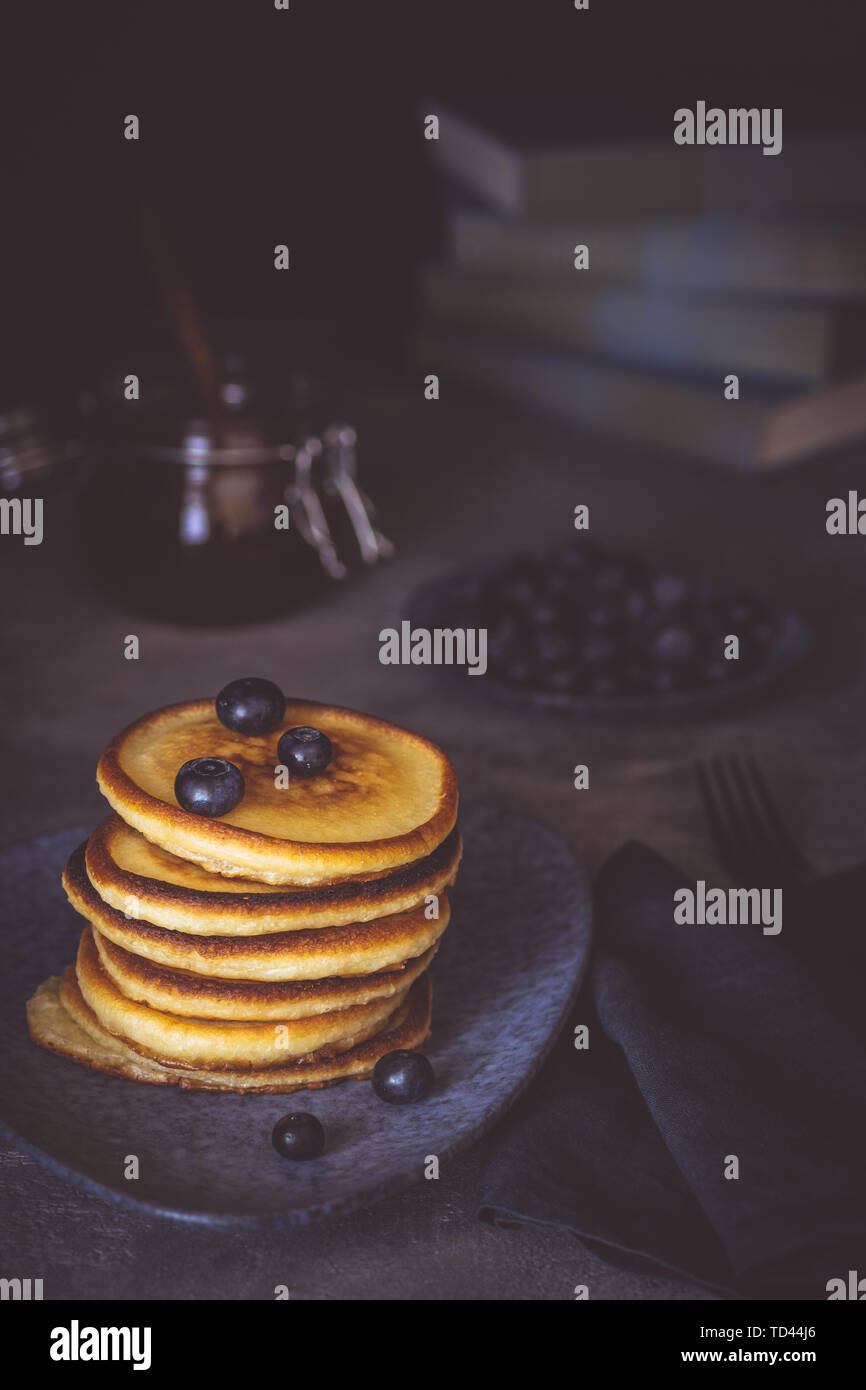 Frische Pfannkuchen mit Ahornsirup und Beeren auf dunklem Hintergrund klassische amerikanische Frühstück Stockfoto