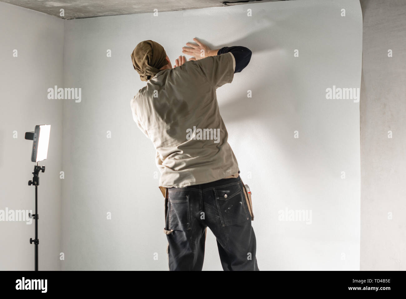 Arbeitnehmer gilt ein Blatt von Tapeten. Mann kleben Wallpaper auf der  Betonwand. Die Wohnung reparieren. Home Renovierung Konzept. Weiße Tapeten  für Lack Stockfotografie - Alamy