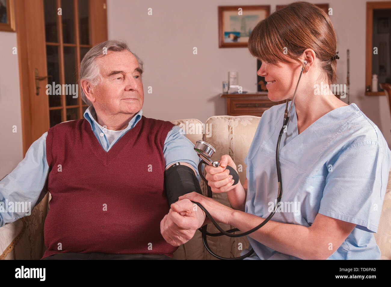 Lächelnd Krankenschwester messen Senioren Blutdruck Stockfoto