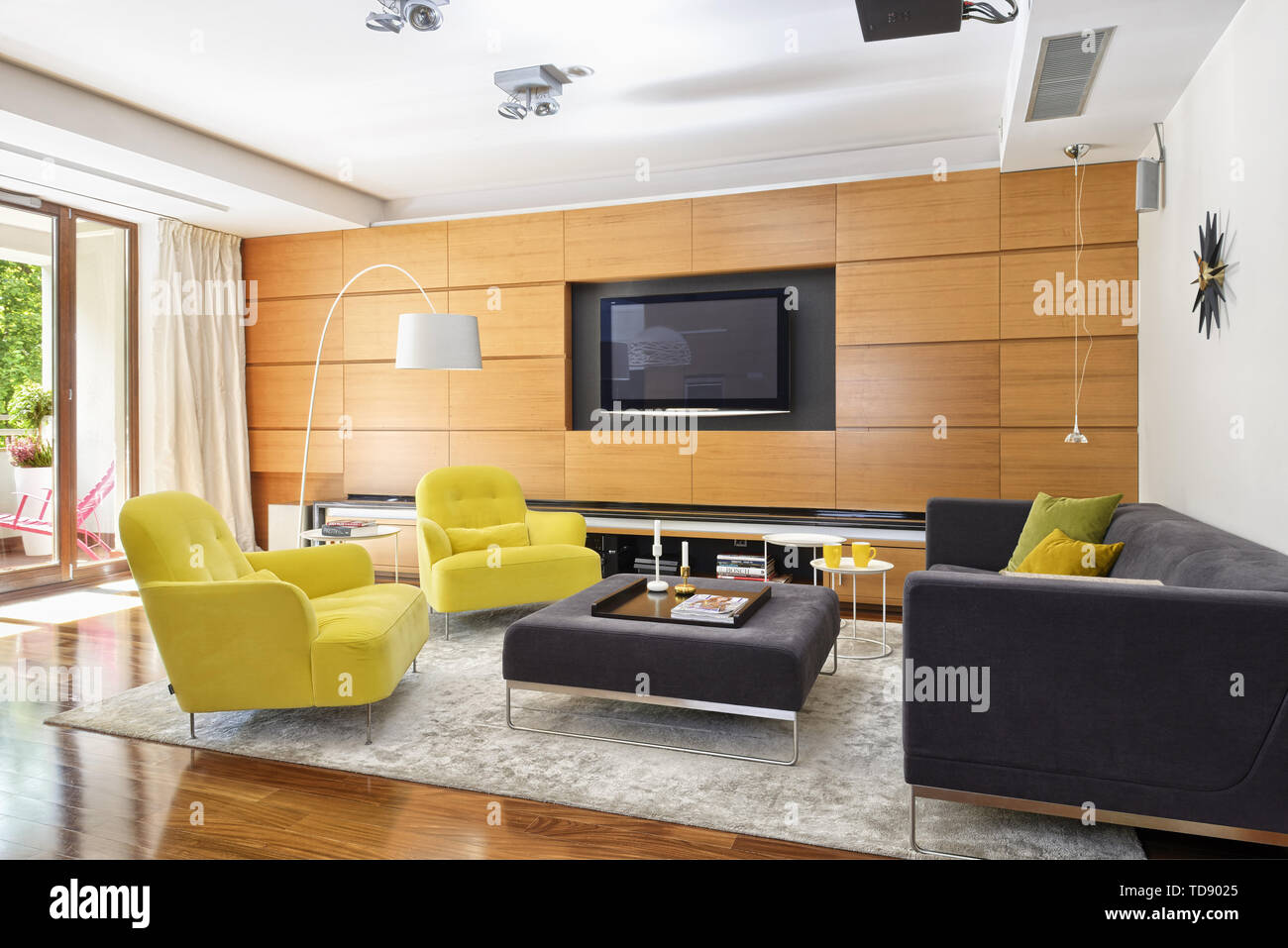 Eingebaute Wandschränke mit TV neben dem Sofa und zwei gelben Sesseln im geräumigen Wohnzimmer britische und irische NUR RECHTE Stockfoto