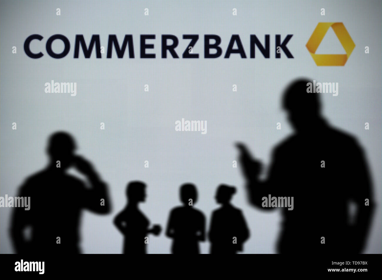 Die Commerzbank-Logo wird auf einer LED-Bildschirm im Hintergrund, während eine Silhouette Person ein Smartphone verwendet im Vordergrund (nur redaktionelle Nutzung) Stockfoto