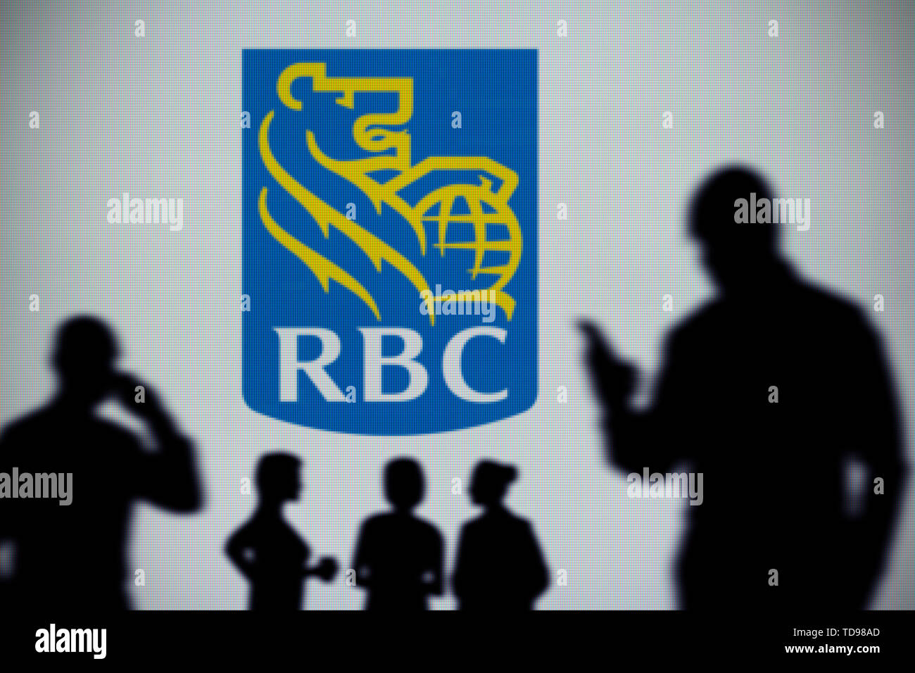 Der RBC Royal Bank Logo ist auf einen LED-Bildschirm im Hintergrund, während eine Silhouette Person ein Smartphone verwendet (nur redaktionelle Nutzung) Stockfoto