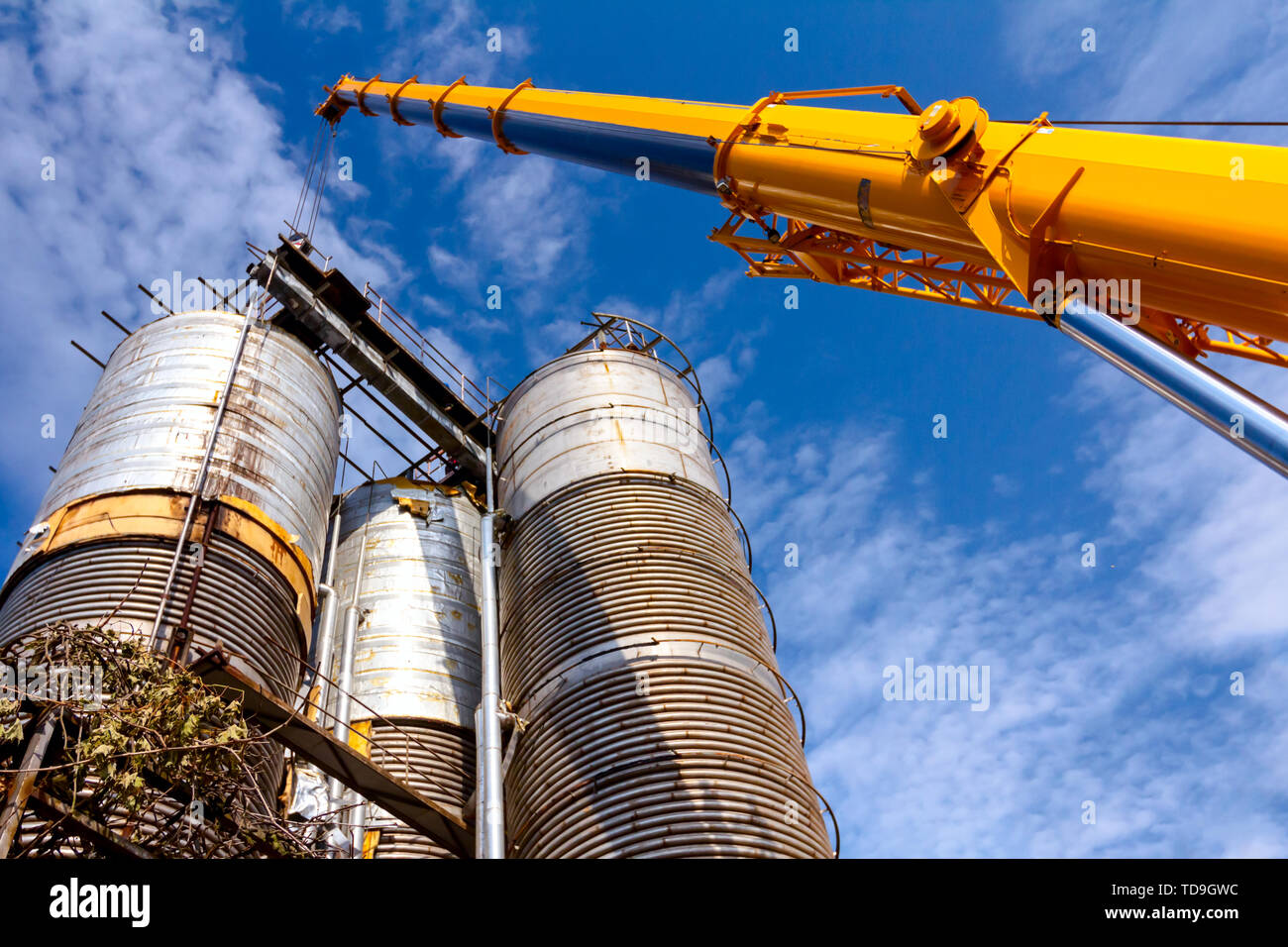 Kran ist und hält die Balance mit heavy metal Silo in industriellen Komplexes. Stockfoto