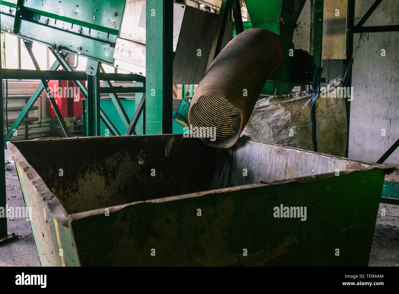 Große grüne Behälter für die Sammlung von Abfällen. Das Rohr, aus dem der Abfall stammt. Sortierung und Verwertung Stockfoto