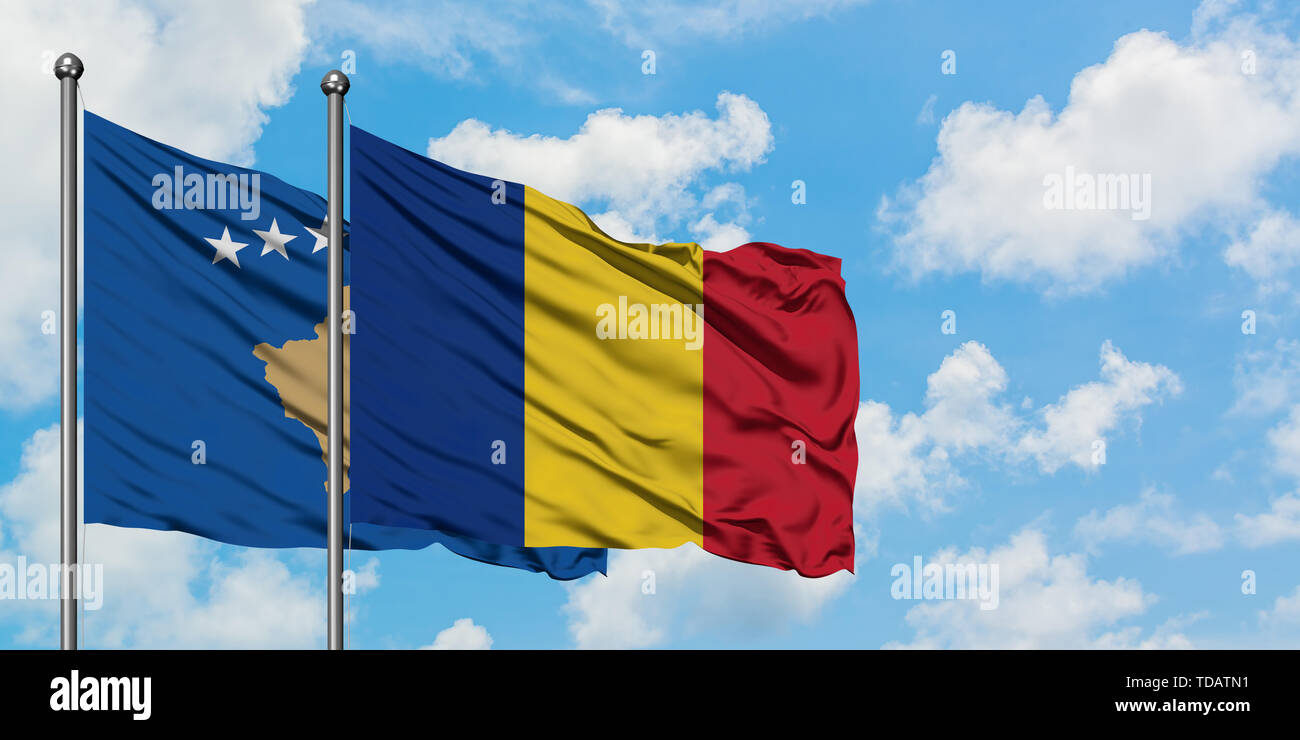 Kosovo und Rumänien Flagge im Wind gegen Weiße bewölkt blauer Himmel zusammen. Diplomatie Konzept, internationale Beziehungen. Stockfoto