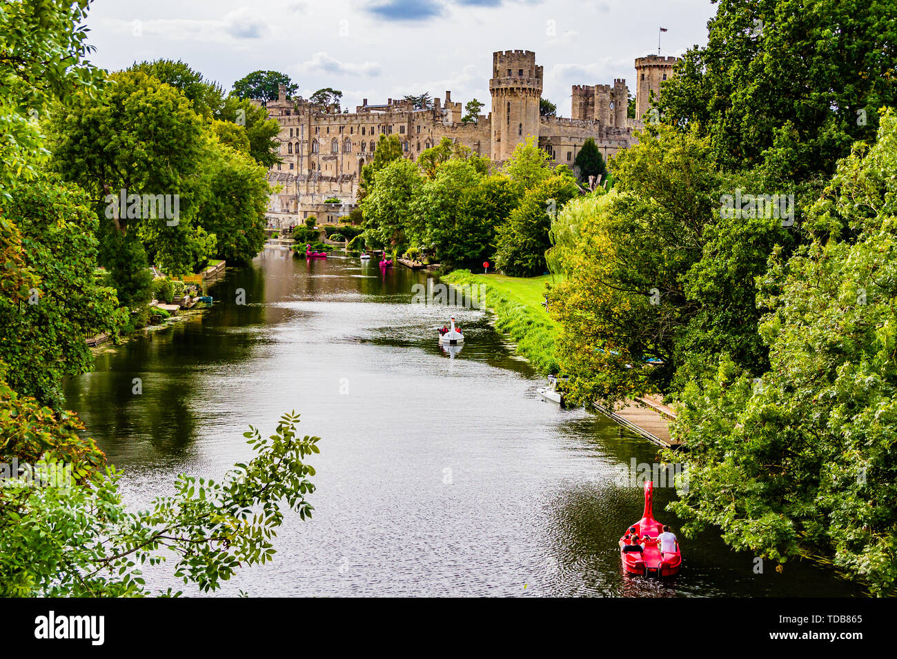 Warwick Castle mit Touristen in Mieten Boote auf dem Fluss Avon. Warwick, Warwickshire, Großbritannien. Sommer 2018. Stockfoto