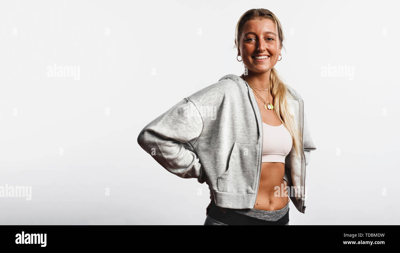Portrait von lächelnden fitness Frau gegen weißen Hintergrund auf den Bund. Lächelnd weibliche Athleten mit Eine gebräunte Haut an Kamera schaut. Stockfoto