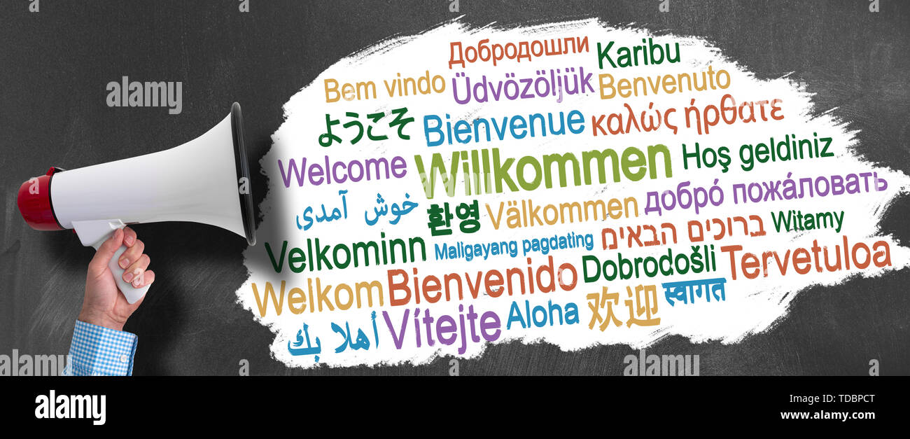 Hand des Kaufmanns holding Megaphon oder Megaphon gegen Tafel mit Wort HERZLICH WILLKOMMEN in verschiedenen Sprachen Stockfoto