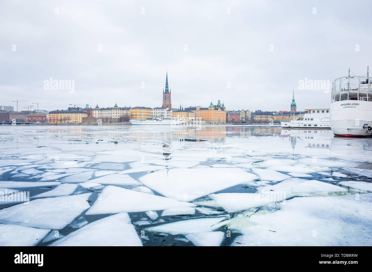 Winter Blick auf Stockholms Altstadt Gamla Stan und Riddarholm Kirche, mit Booten in den zugefrorenen See, die zu der Ostsee günstig. Stockfoto